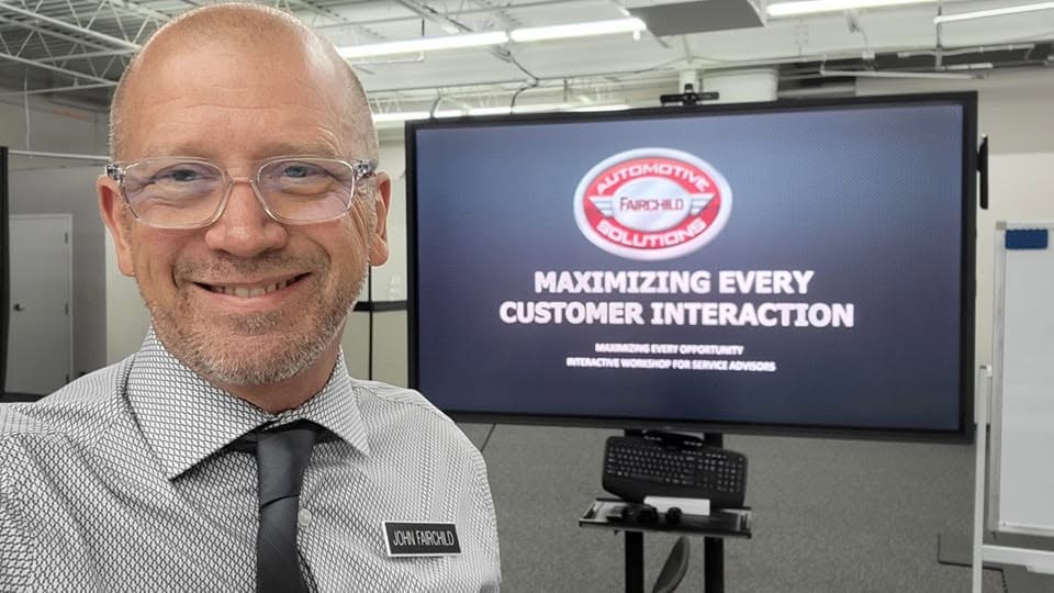 John Fairchild at the Pinnacle Training Center, beside the Maximizing Every Customer Interaction workshop slide